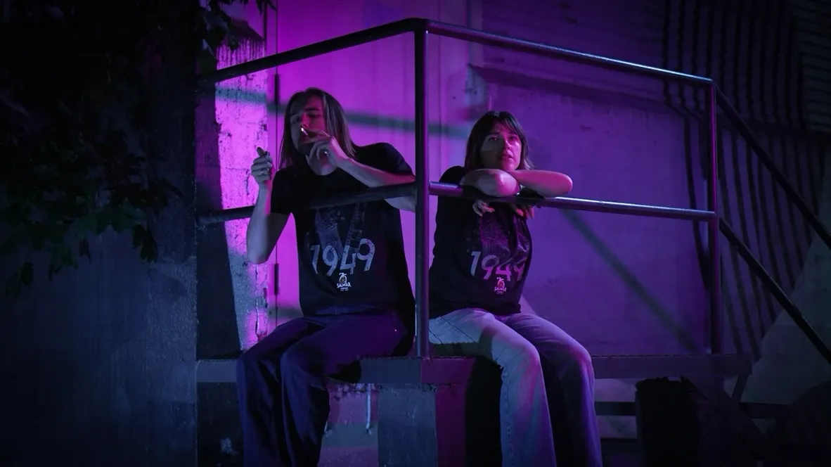 Two young theatre employees on the back stairs under violet light